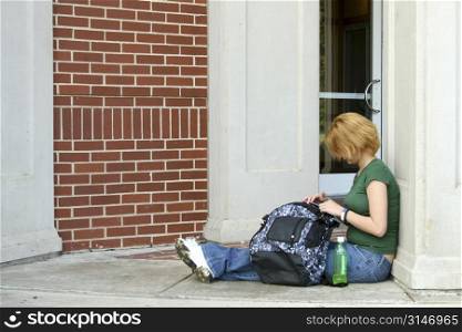 Teen girl sitting on porch with bag