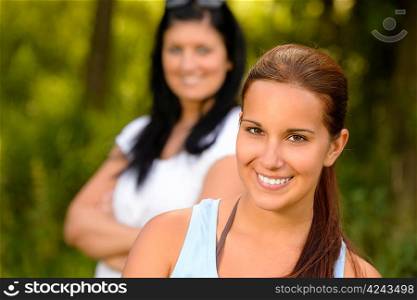 Teen girl smiling with mother in background relaxing outdoors youth