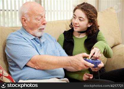 Teen girl teaching her grandfather how to play video games.