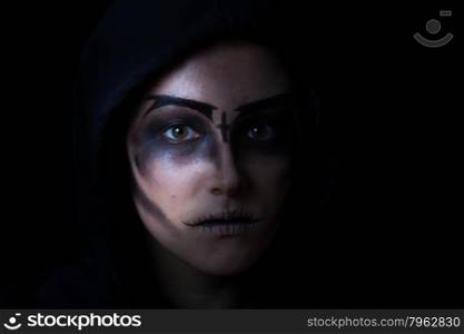 Teen girl wearing hoodie with scary face makeup on black background.
