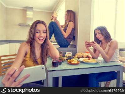 teen girls best friends lunch eating at kitchen. teen girls best friends having lunch eating at kitchen with smartphone