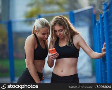 teen girls group of friends on athletics training using smart phone