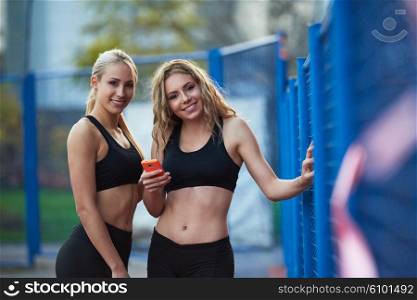 teen girls group of friends on athletics training using smart phone
