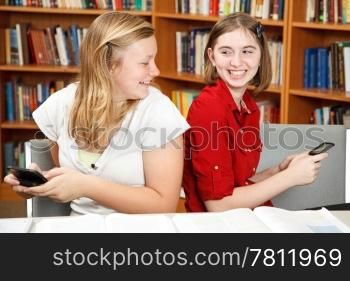 Teen girls having a conversation via text in the library.