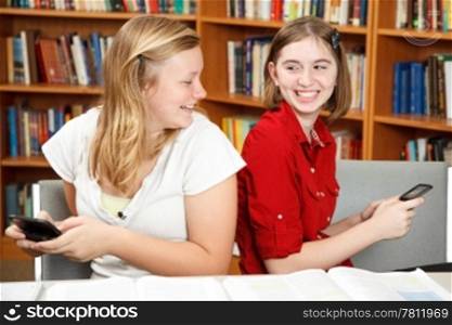 Teen girls having a conversation via text in the library.