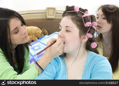 Teen girls in pajamas giving friend a make-over at sleepover.