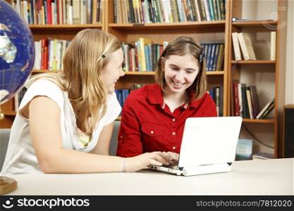 Teen girls using the computer in the school library.