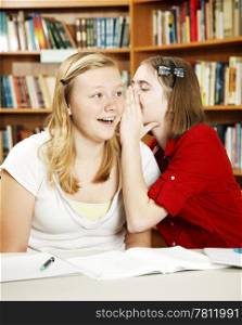 Teen girls whispering and telling secrets in school.