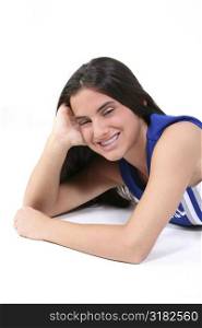 Teen in cheerleading uniform laying on white with big smile wearing braces.