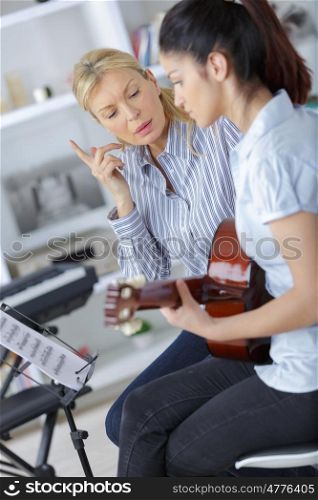 teen learning how to play the guitar with teacher