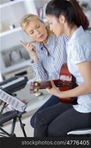 teen learning how to play the guitar with teacher