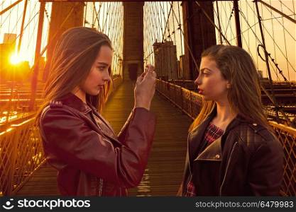 Teen tourist girls taking photo in Brooklyn bridge NY. Teen tourist girls taking photo with smartphone in Brooklyn bridge of New York photomount