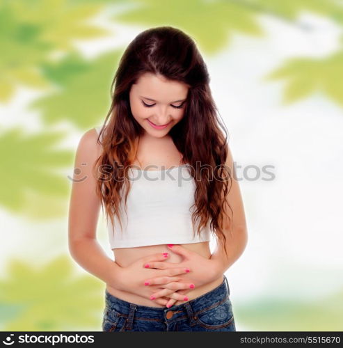 Teen woman touching her belly on a background wiht leaves