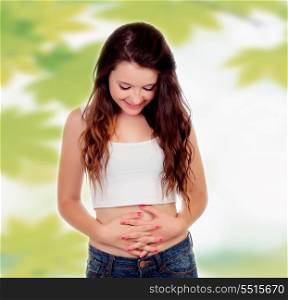 Teen woman touching her belly on a background wiht leaves