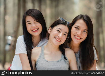 Teenage Asian female happy smiling to camera, Group of young Asian friends camping or picnic together in forest. Women do adventure activity and travel on holidays vacation in summer.