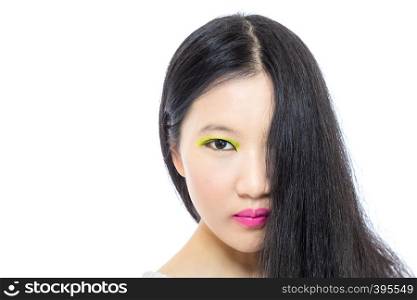 Teenage Asian high school girl wearing pink and green makeup with hair hanging in front of half face