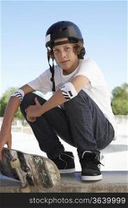 Teenage boy (16-17) with skateboard at skateboard park, portrait