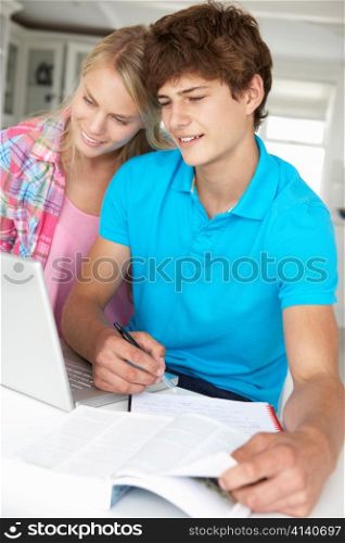 Teenage boy and girl doing homework with laptop