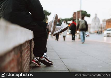 teenage boy and girl sit together on the street where you can see their legs