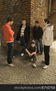 Teenage boy crouching with his friends standing around him