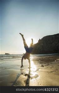 Teenage boy doing handstand at beach, Camaret-sur-mer, Brittany, France