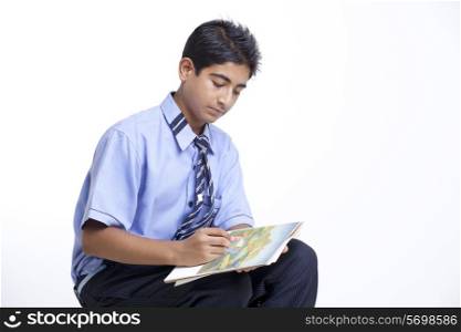 Teenage boy drawing in book against white background