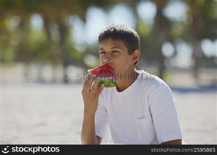 Teenage boy eating a slice of watermelon