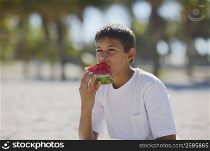 Teenage boy eating a slice of watermelon