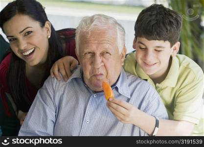 Teenage boy feeding a yellow bell pepper to his grandfather