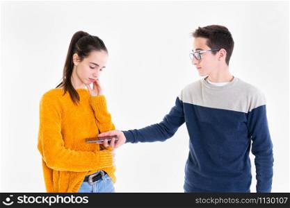 Teenage boy hands his smartphone to a concerned looking teenage girl on a light background.. Teenage boy hands a smartphone to a teenage girl