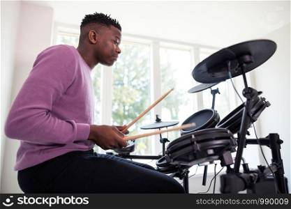 Teenage Boy Having Fun Playing Electronic Drum Kit At Home
