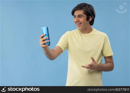 Teenage boy having video call on Smartphone against blue background