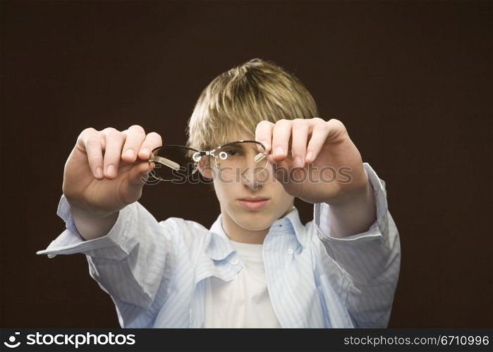Teenage boy holding glasses