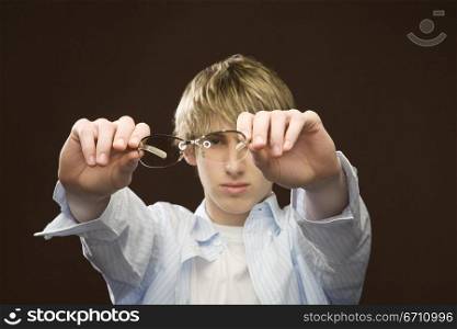 Teenage boy holding glasses