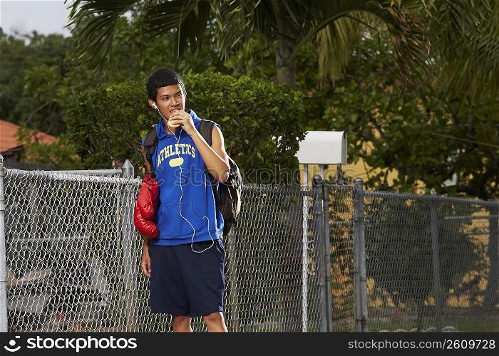 Teenage boy listening an ipod and eating empanada