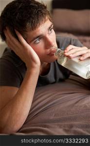 Teenage Boy Lying In Bedroom Drinking