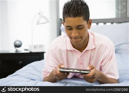 Teenage Boy Lying On Bed Playing Video Game