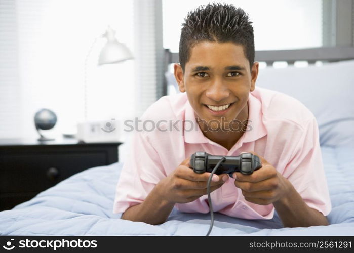 Teenage Boy Lying On Bed Playing Video Game