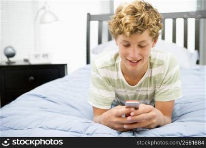 Teenage Boy Lying On Bed Using Mobile Phone