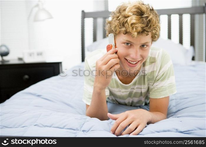 Teenage Boy Lying On Bed Using Mobile Phone