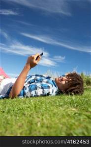 Teenage boy lying on grass with phone