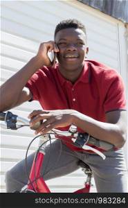 Teenage Boy On Bike Talking on Mobile Phone Outdoors