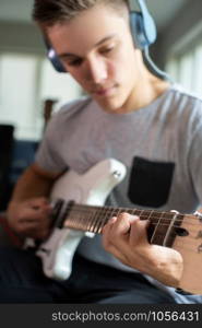 Teenage Boy Playing Guitar And Recording Music At Home