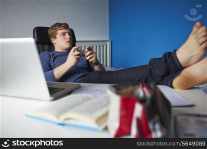Teenage Boy Playing Video Game Instead Of Studying