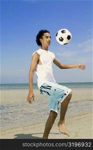 Teenage boy playing with a soccer ball on the beach