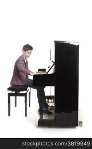 teenage boy plays the piano in studio with white background