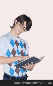 Teenage boy standing and reading a book