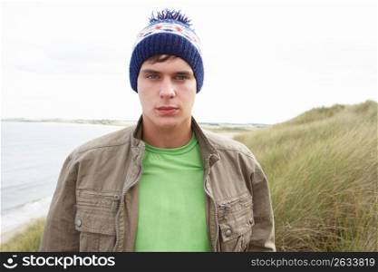 Teenage Boy Standing In Sand Dunes Wearing Woolly Hat