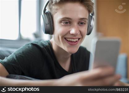 Teenage Boy Streaming Music From Mobile Phone To Wireless Headphones