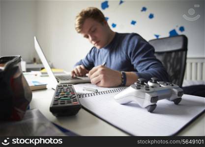 Teenage Boy Studying In Bedroom Using Laptop
